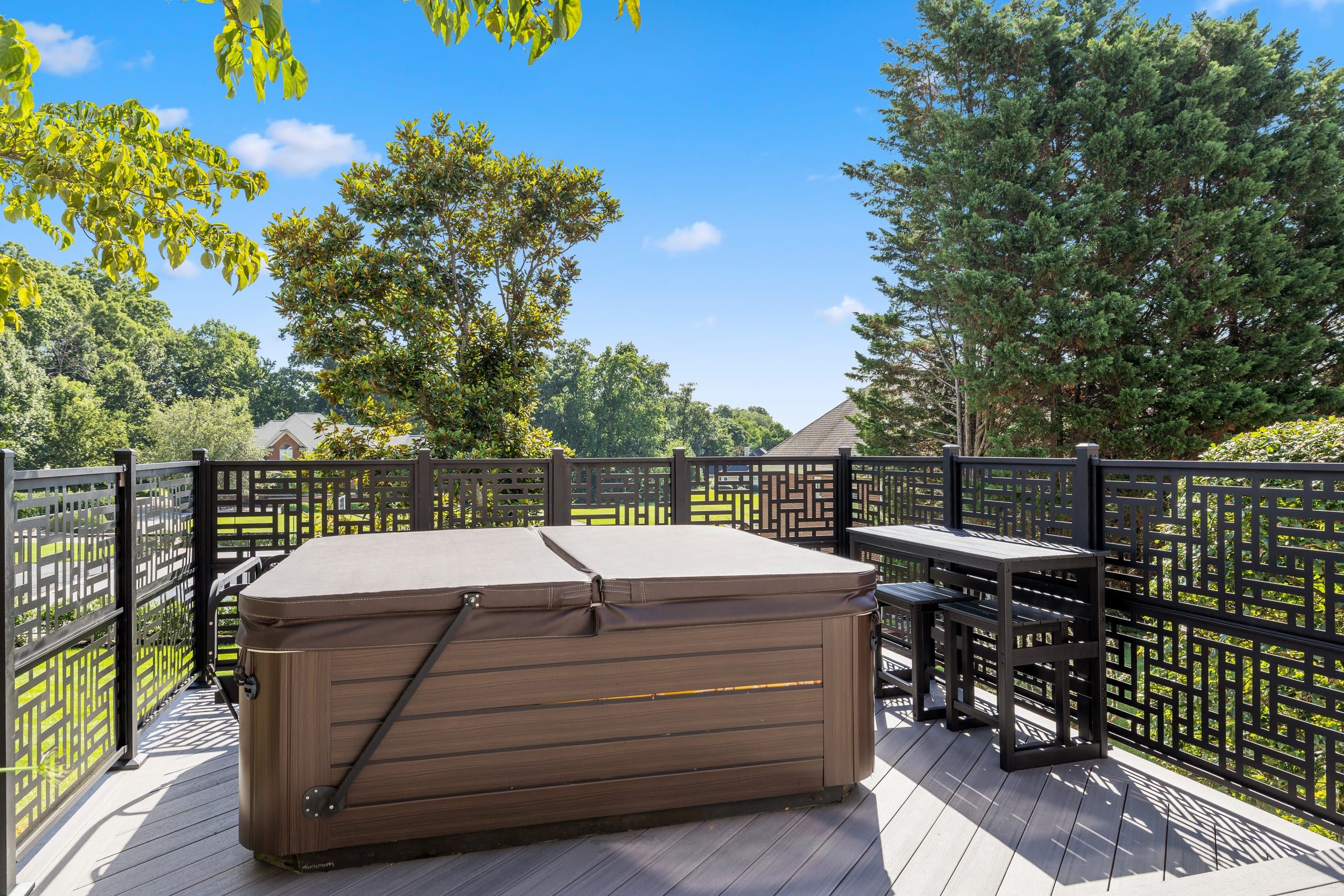Hot tub on the Wilshire deck enclosed by black laser-cut metal privacy screens with a geometric pattern